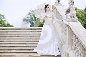 Woman in white Victorian dress with umbrella