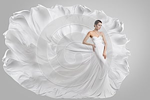 Woman in White Wedding Dress. Fashion Bride Model in Long Gown Flying in Air on Wind. Gray Background. Side View