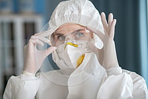 Woman in white workwear putting on protective eyewear