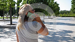 A woman who talks on the phone while walking in the park.