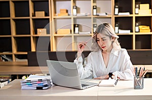 Woman who is tired and overthinking from working with tablet and laptop at office