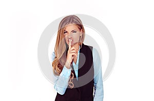 Woman wide eyed asking for silence or secrecy with finger on lips hush hand gesture white background wall. Pretty girl placing