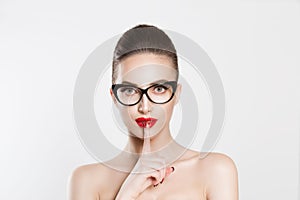 Woman wide eyed asking for silence secrecy with finger on lips hush hand gesture white isolated background wall. Pretty girl