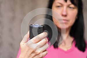 A woman will use a stun gun with a powerful electric discharge. The girl holds a personal taser in her hands to protect against