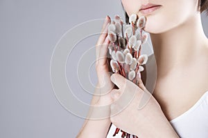 Woman with willow branches in hands on a gray background