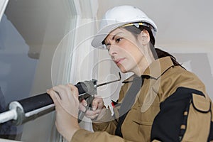 Woman window installer applying caulking
