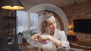 A woman winds curls on a brush attachment using a multi-styler hairdryer at home