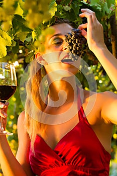 Woman with wine glass eating grapes