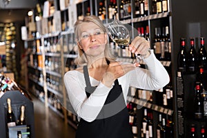 Woman wine producer inspecting quality of wine