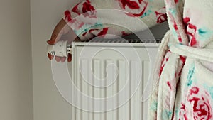 A woman in a winter bathrobe turns the heat in the radiator, Creative concept, High energy prices and home heating costs