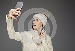 A woman in winter clothes taking pictures on smartphone.