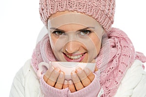 Woman in winter clothing holding cup of tea