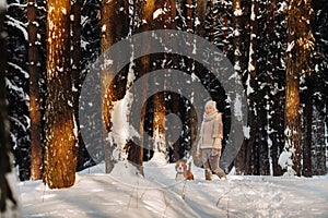 A woman on a winter day with her pet dog beagle in the winter forest playing