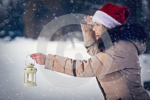 woman on winter forest with lantern â€“winter holidays, Christmas and people concept.