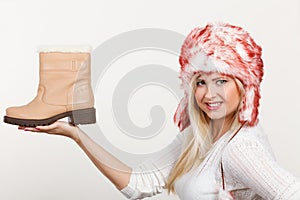 Woman in winter hat holding beige boots.