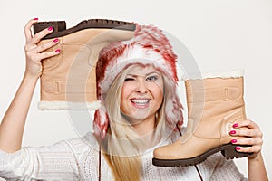 Woman in winter hat holding beige boots.