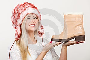 Woman in winter hat holding beige boots.