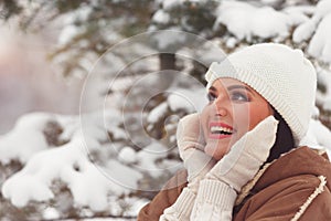 Woman in winter park closing face with mittens