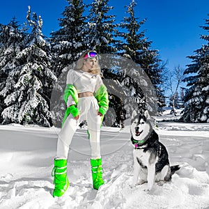 Woman winter portrait with Husky dog. Winter fashion model with winter outfit and ski goggles. Attractive young woman in