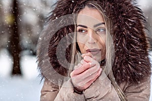 Woman in winter snow day blow on her cold hands close-up