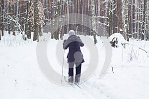 A woman in the winter time goes skiing. View from the back