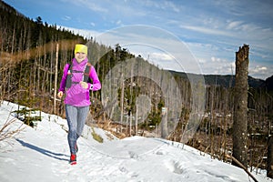 Woman winter trail running in mountains on snow