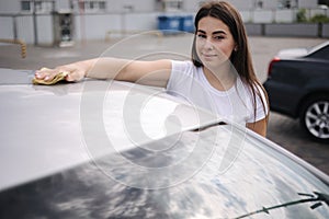 Woman wipes a windshield of his car with a rag in a showroom at a self-service car wash