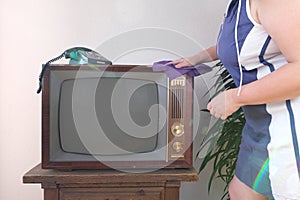 woman wiping down old television set, taking care household chores and cleaning vintage electronics, retro style Television,