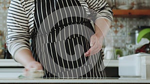 A woman is wiping her work surface and flicking the napkin into the kitchen sink. Home kitchen interior