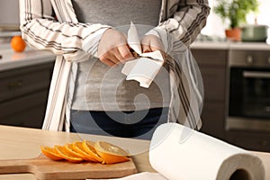 Woman wiping knife with paper towel in kitchen