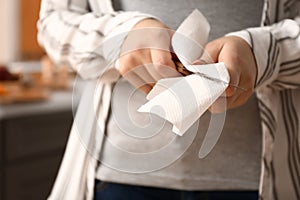 Woman wiping knife with paper towel in kitchen, closeup