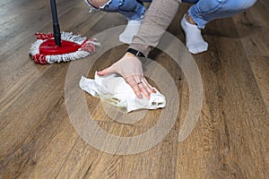 A woman wiping piss on a puppy off modern water resistant vinyl panels with a paper towel and mop. photo