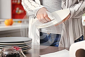 Woman wiping plate with paper towel in kitchen