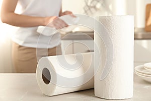 Woman wiping plate with towel, focus on paper rolls