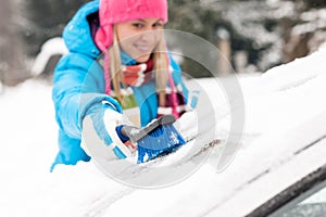 Woman wiping snow car window using brush