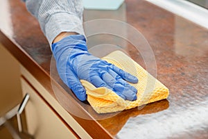 Woman wiping table countertop in kitchen by wet cloth rag. Female charwoman hand cleaning disinfect office home restaurant photo