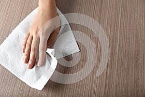 Woman wiping wooden table with paper towel