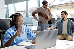 Woman in wireless headset talking on laptop computer talk by webcam with her customers