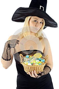 Woman in witch costume holding a basket of sweets for trick or treat on halloween