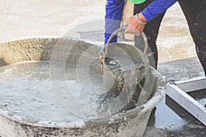 Woman woker scoop mixed cement into a bucket.