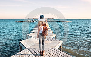 Woman on wooden pier with hat and bag