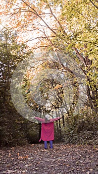 Woman in the woods enjoying a walk with sunshine in autumn