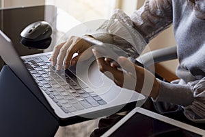 woman work on laptop computer, hand holding mobile smart phone