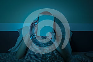 Woman work with tablet or computer on the bed at night