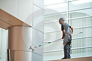 Woman worker cleaning indoor window