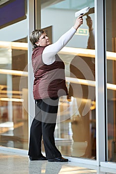 Woman worker cleaning indoor window