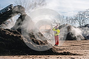 Woman worker with clipboard in industrial compost plant