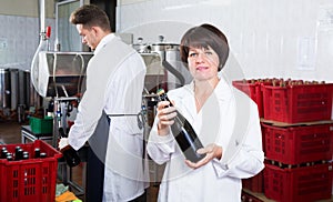 Woman worker displaying wine bottle