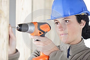 Woman worker drilling something at construction site
