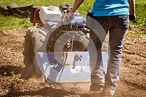 Woman worker driving rototiller tractor unit preparing soil on o photo